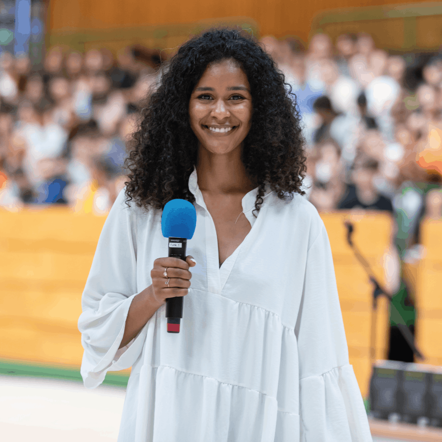 Lijana Kaggwa hält ein Mikrofon bei einem Vortrag vor Schülern – Love Always Wins e.V. engagiert gegen Cybermobbing